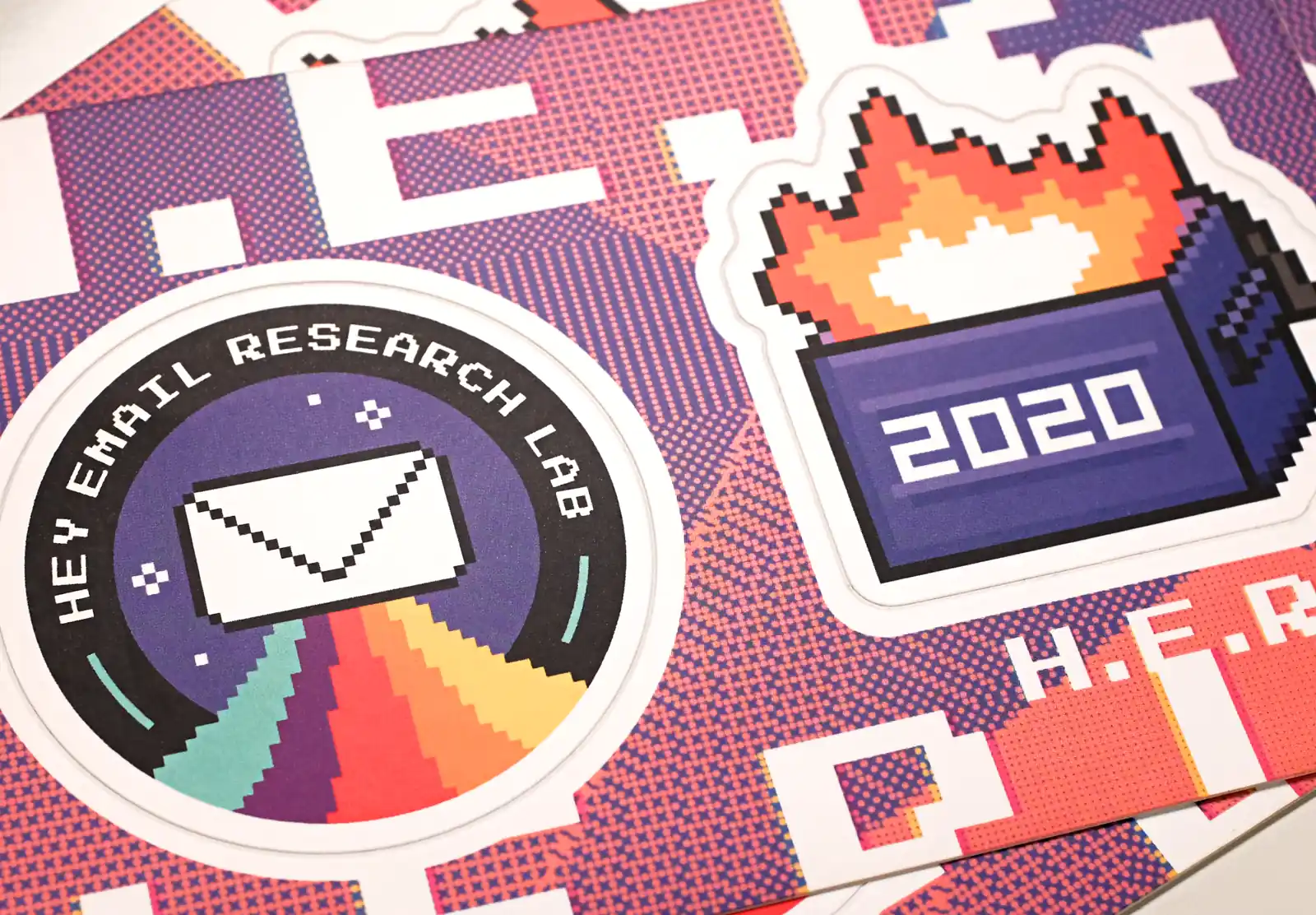 A close up of a sticker sheet with two stickers; an enevelope rocketing into space on rainbow thrust, and a dumpster fire.